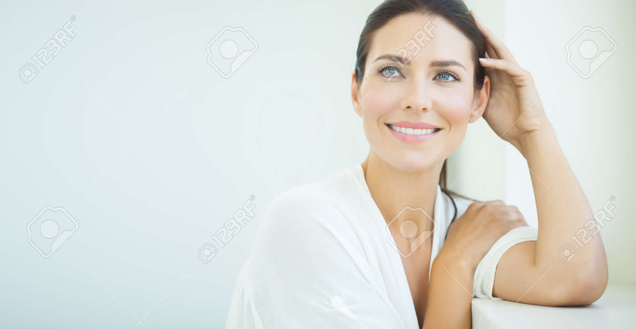 Beautiful woman sitting at window. Light blue and white day light and high key. - 59851544 Beautiful woman sitting at window. Light blue and white day light and high key. - 59851544