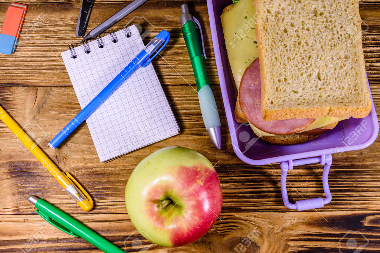 Ripe apple, different stationeries and lunch box with sandwiches on wooden table. Top view - 150620794 Ripe apple, different stationeries and lunch box with sandwiches on wooden table. Top view - 150620794