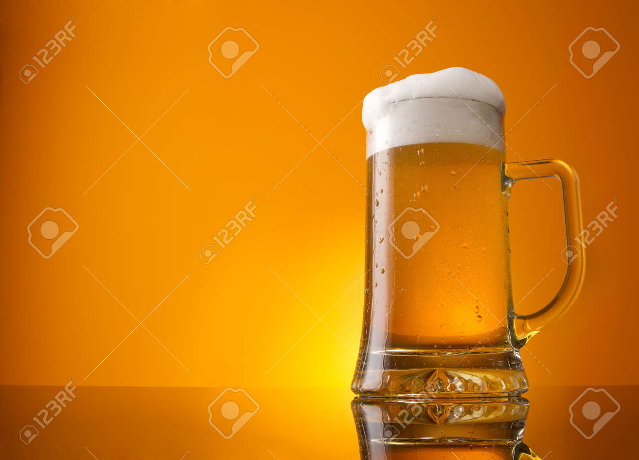 Glass of beer close-up with froth over orange background - 10693387 Glass of beer close-up with froth over orange background - 10693387