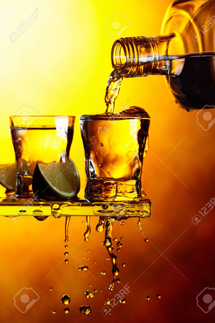 Tequila With Lime Slices On A Yellow Background Pouring A Strong Alcoholic Drink Into Small Glasses Copy Space Stock Photo Picture And Royalty Free Image Image