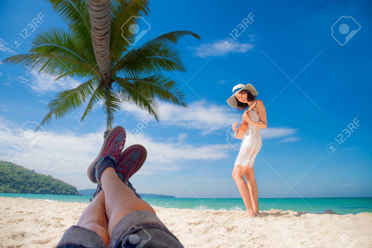 カップルの恋人は 海のビーチで一緒に楽しみ 陽気な新婚旅行 休日のバレンタインの機会にウクレレを演奏歌と歌 の写真素材 画像素材 Image