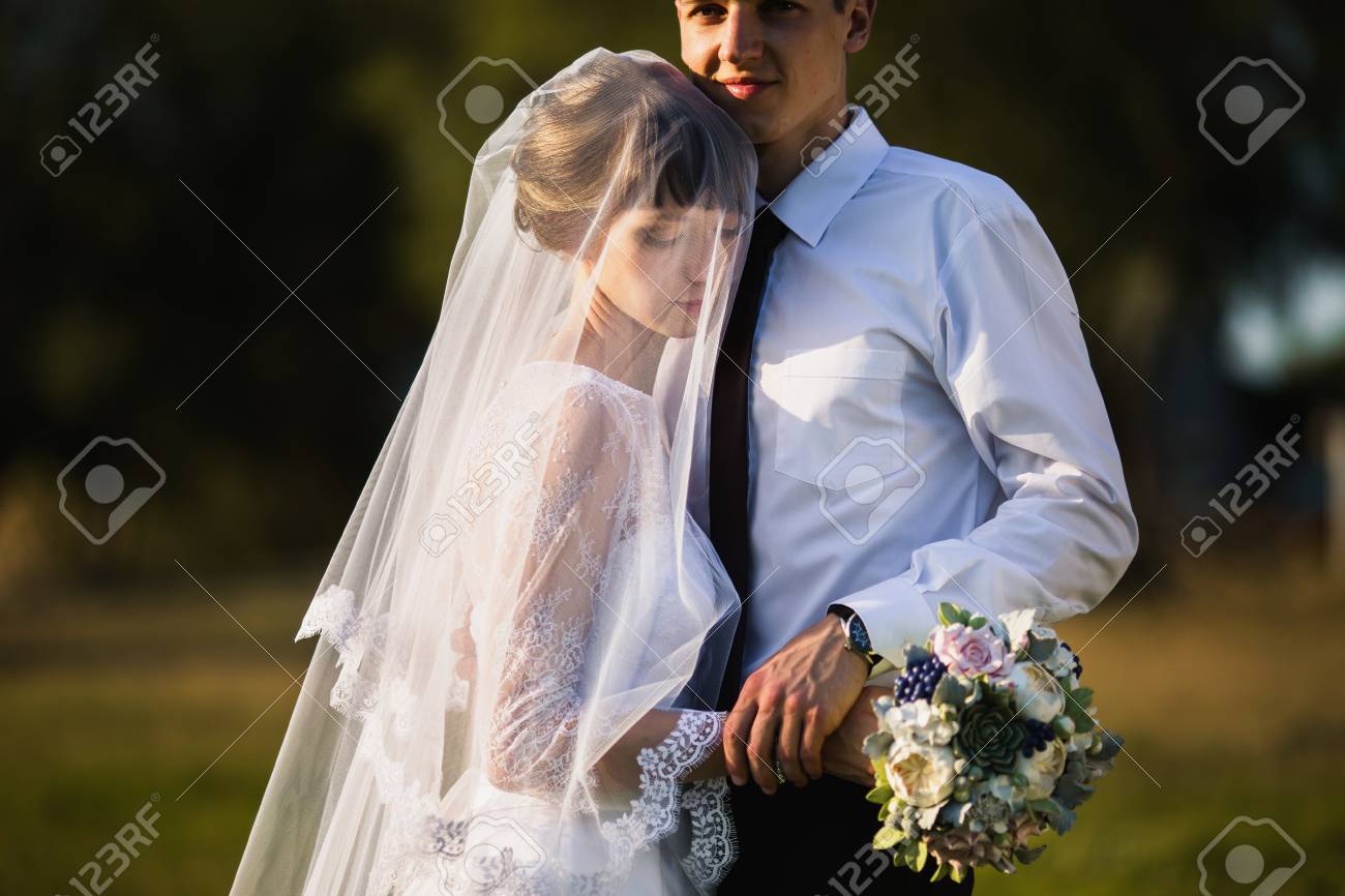 太陽の光で自然に結婚式のカップル 男と女の間が大好きです ウェディング ドレスの花嫁 スーツの新郎 美しい結婚式の花束 自然な夏の背景 の写真素材 画像素材 Image