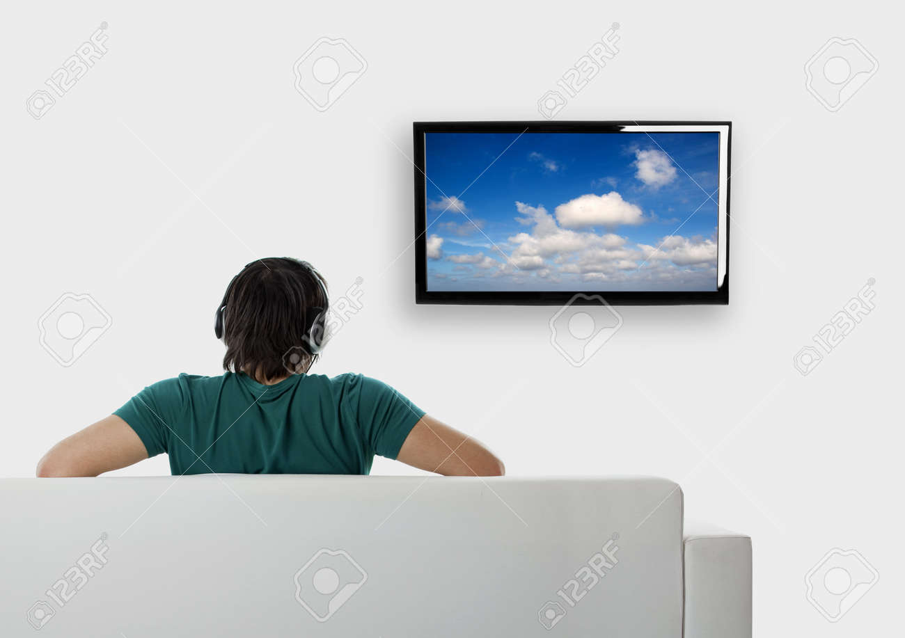 Rear view from a young man seated on the couch watching tv - 8372365 Rear view from a young man seated on the couch watching tv - 8372365