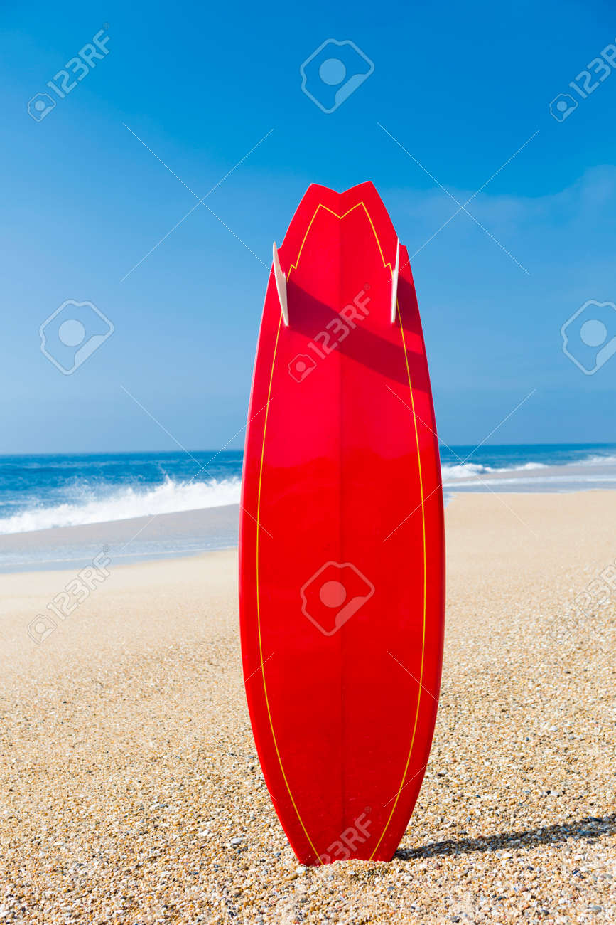 beach landscape with a red surfboard on the sand stock photo