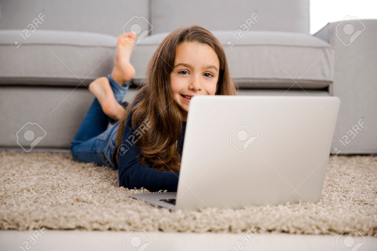 Happy little girl at home working with a laptop - 62112776 Happy little girl at home working with a laptop - 62112776