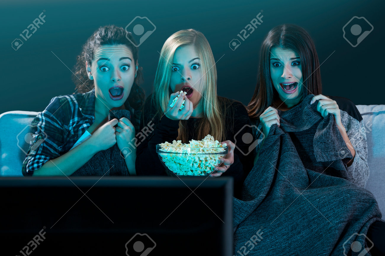 Teenage girls watching horror movie with popcorn - 64609134 Teenage girls watching horror movie with popcorn - 64609134
