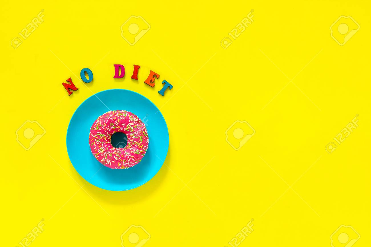 pink donut on blue plate and text no diet still life on yellow blue no yellow