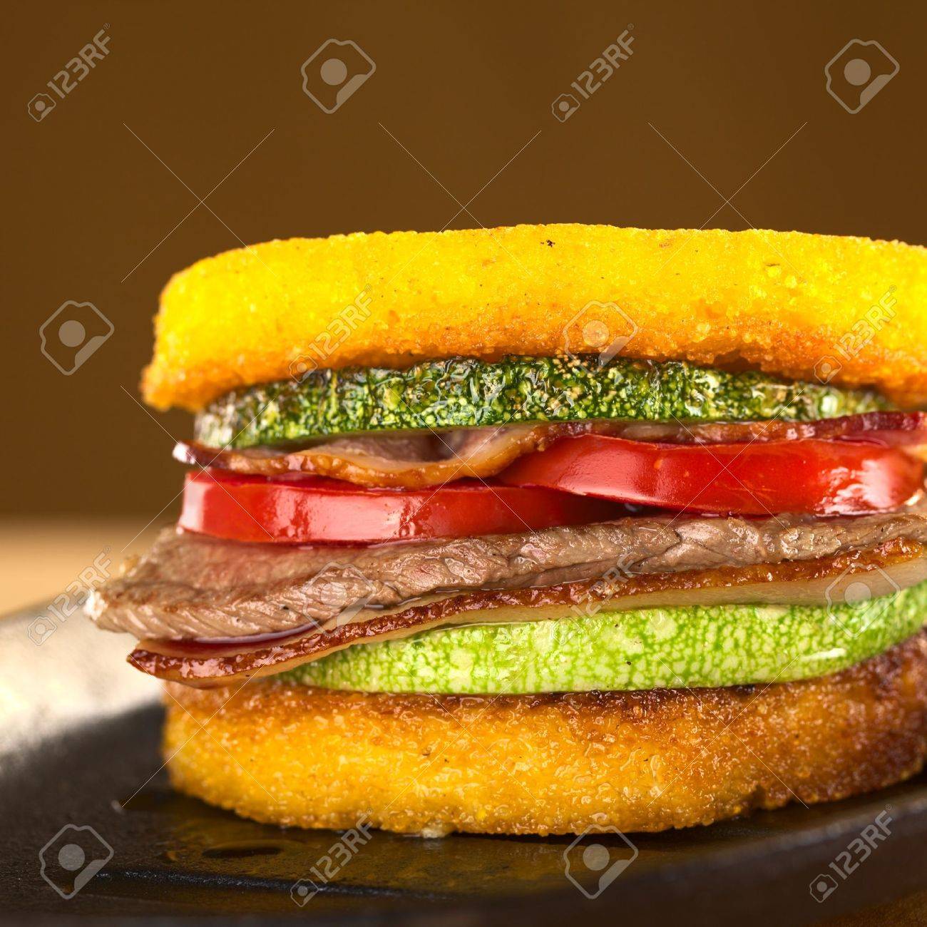 ポレンタのハンバーガー揚げズッキーニ ベーコン 牛肉とトマト セレクティブ フォーカス ハンバーガーの前面にフォーカス の写真素材 画像素材 Image