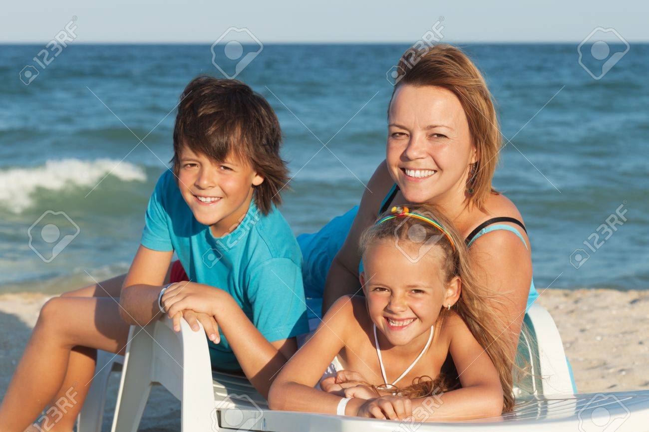 Happy woman and kids relaxing on a deck chair by the sea - summer beach portrait - 20905241 Happy woman and kids relaxing on a deck chair by the sea - summer beach portrait - 20905241