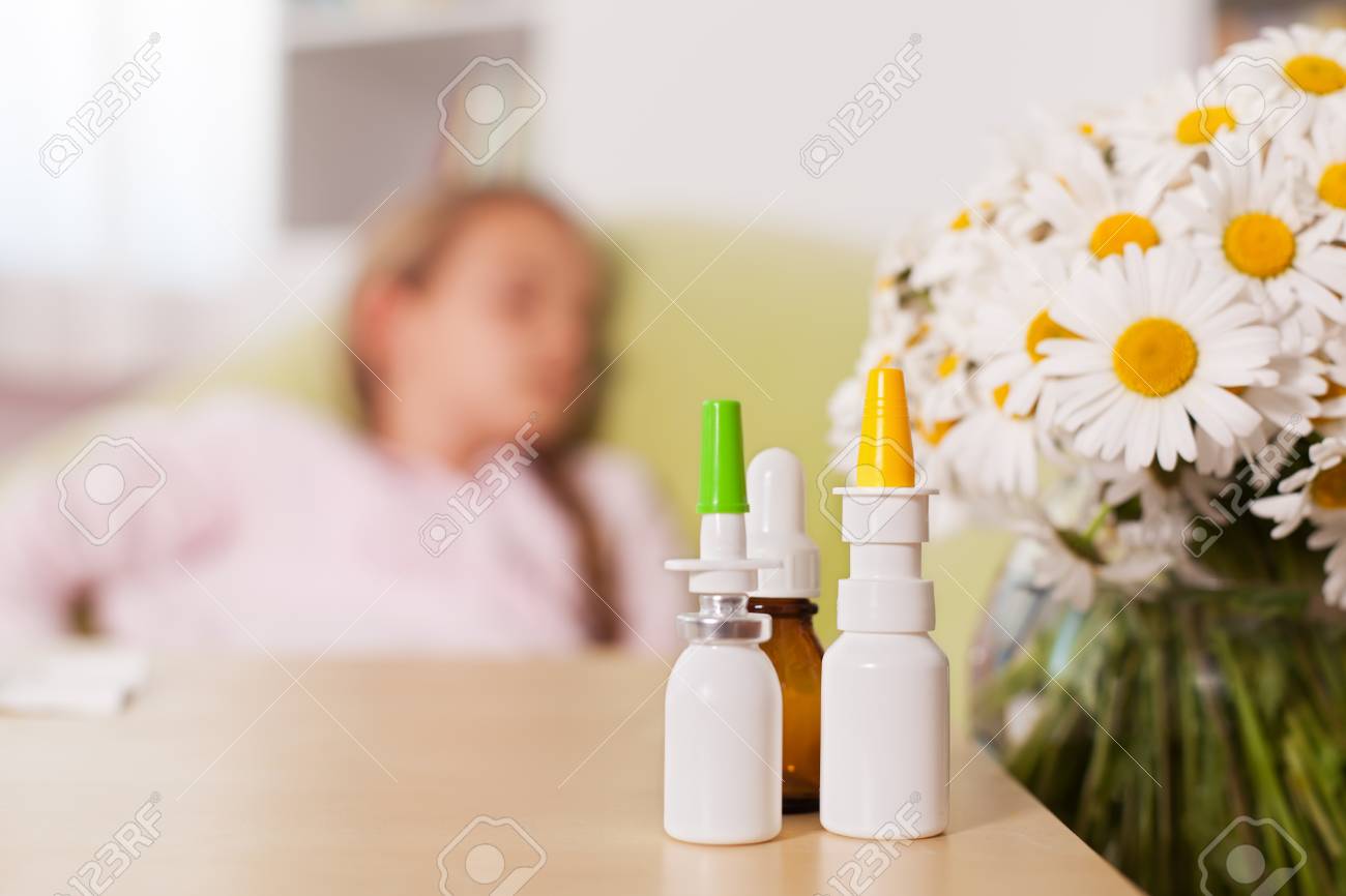 Allergy season concept with blurry person resting in background and medication bottles in the foreground - 98429962 Allergy season concept with blurry person resting in background and medication bottles in the foreground - 98429962