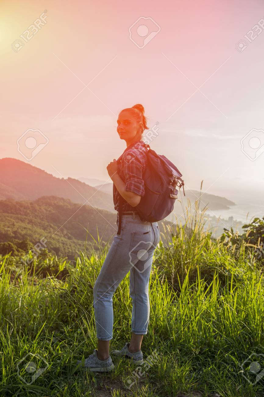 Hipster Young Girl With Backpack Enjoying Sunset On Peak Of Foggy