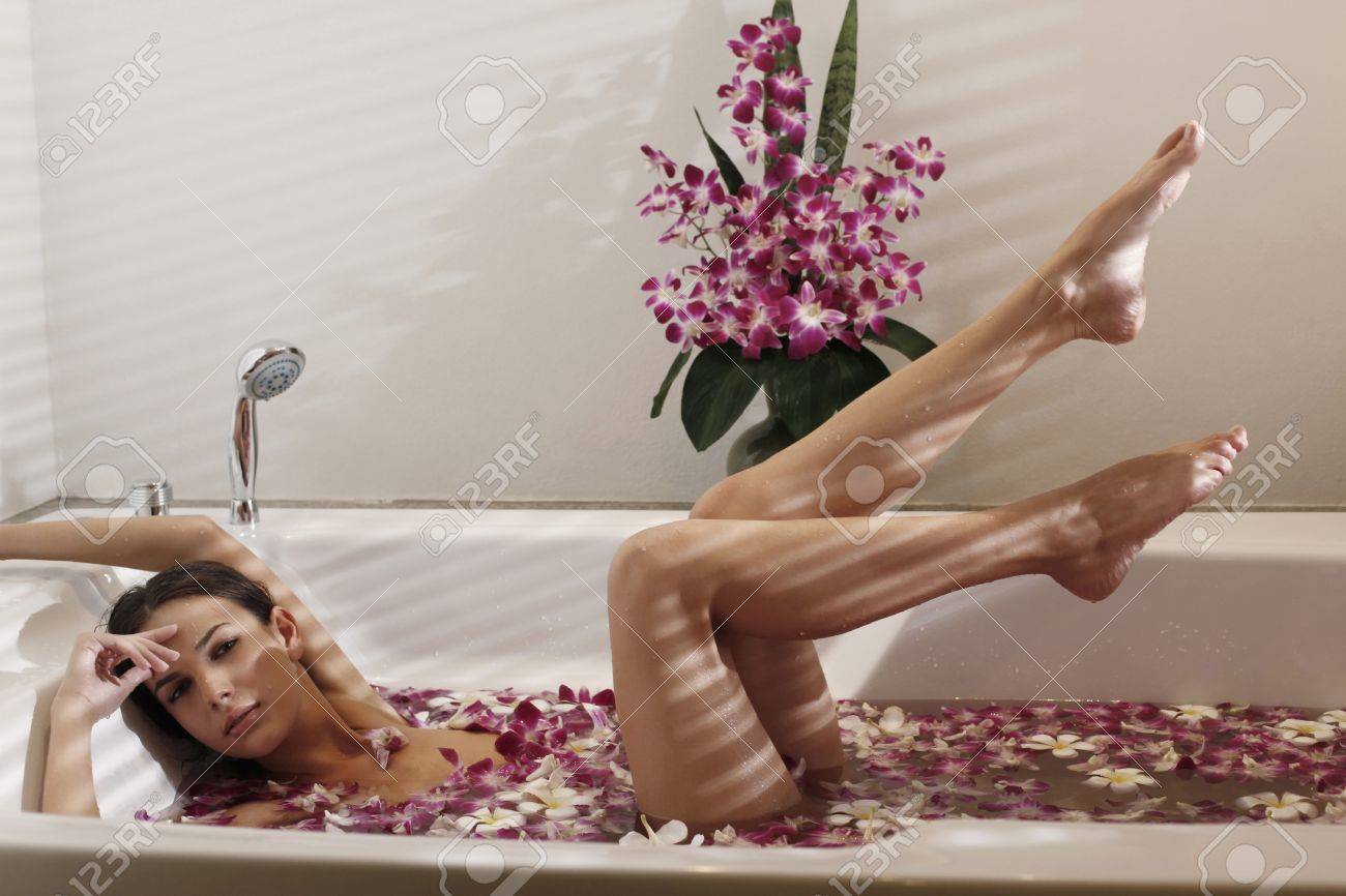 archivio fotografico donna relax nella vasca da bagno con petali di fiori di sollevare le gambe