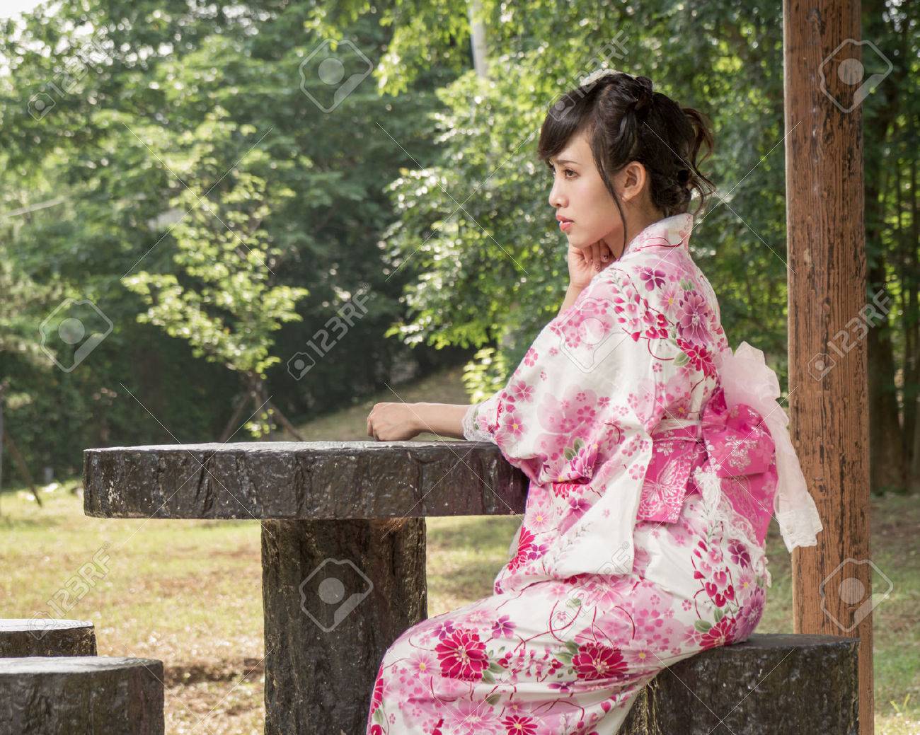 Asian Woman In A Kimono Sitting In A Japanese Style Garden Stock Photo, Pic...