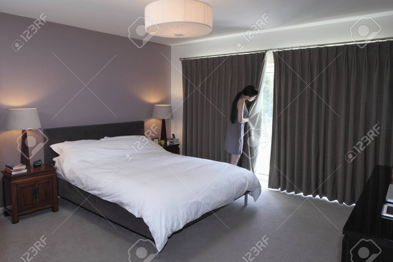 Woman Peeping Behind Bedroom Curtain