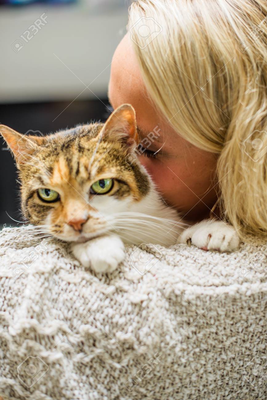 Over the shoulder of woman nuzzling cat