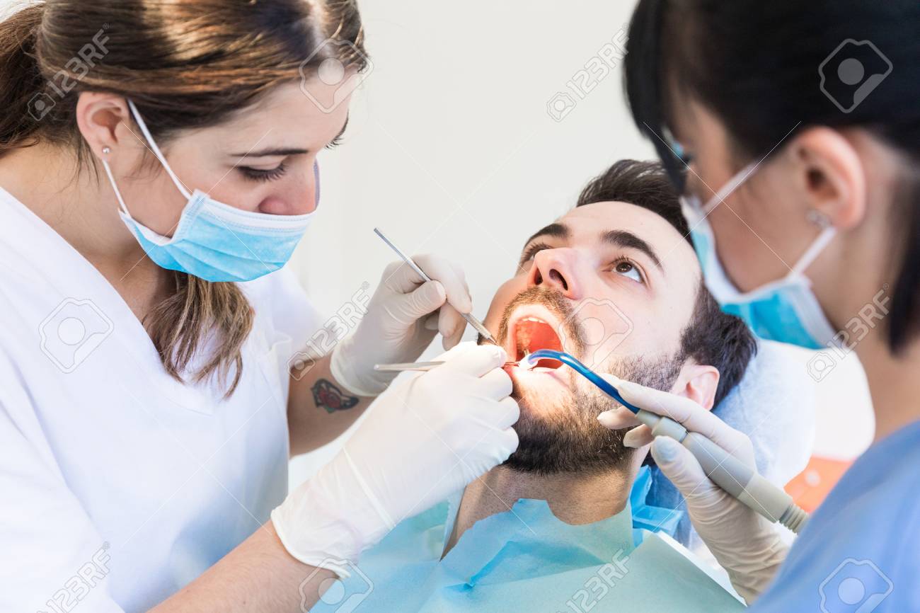 dentist and dental nurse giving male patient dental examination dentist nurse