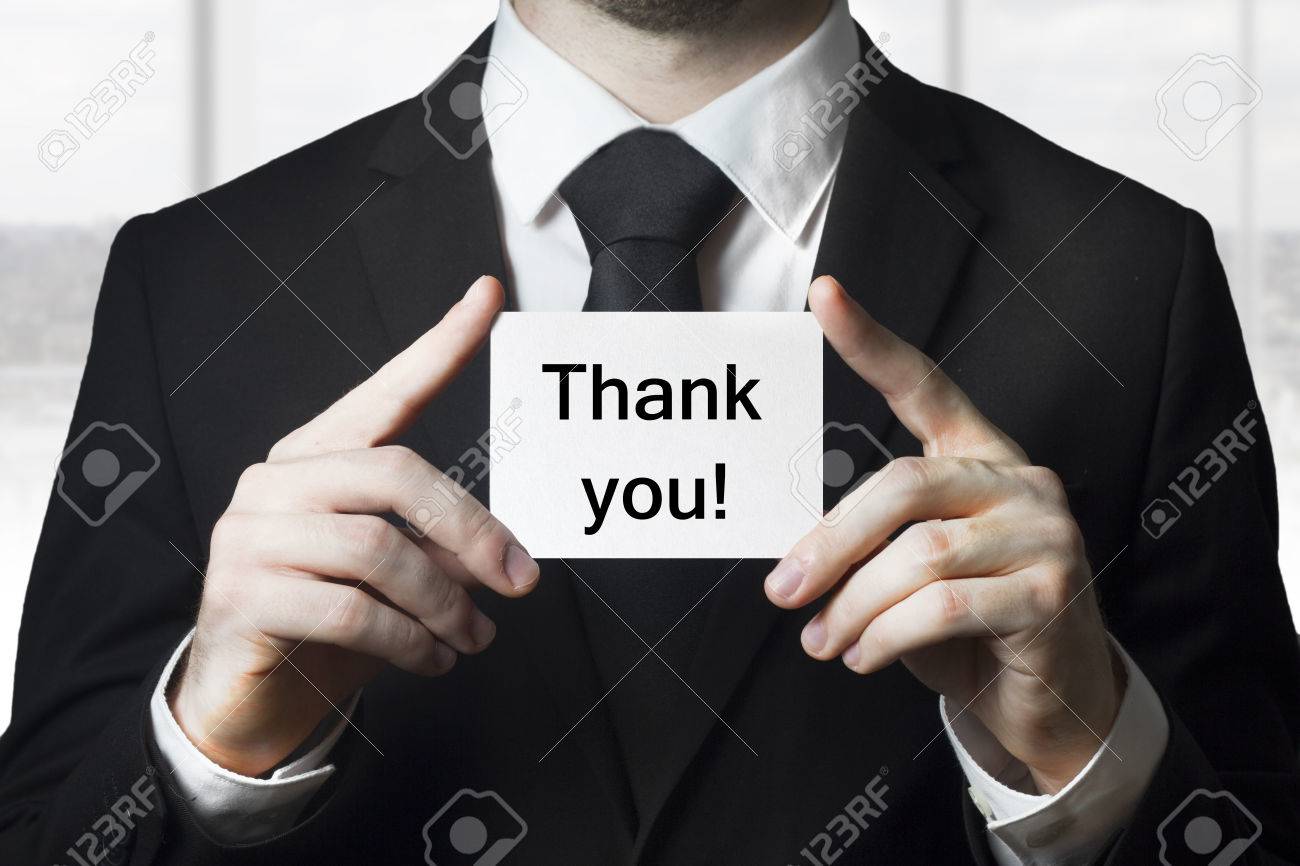 businessman in black suit holding small white card thank you - 30485531 businessman in black suit holding small white card thank you - 30485531