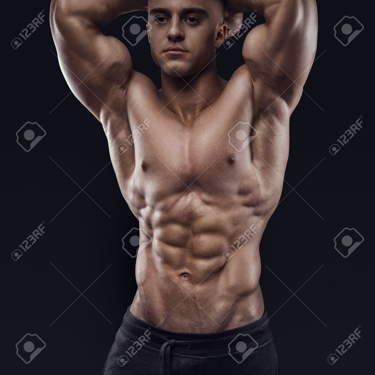 Sexy shirtless male model young bodybuilder posing over black background studio shot on black background