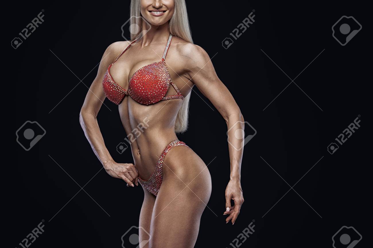 クローズアップ写真完璧な女性ビキニモデルは 黒の背景にポーズ魅力的な女性アスリートボディービルダーポーズは 彼女によく訓練された体型の腕の胸の胸の戦利品コピースペース赤い水着を示しています の写真素材 画像素材 Image 95749724