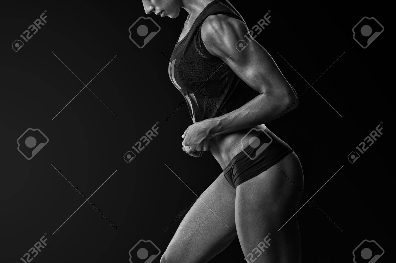 自信を持つ運動女性ボディービルダー 6 パック腹筋ポーズ スポーツ服ブラジャー短い立ち上に手頭上黒と白のクローズアップショットで若いフィットネスの女性を提起 の写真素材 画像素材 Image