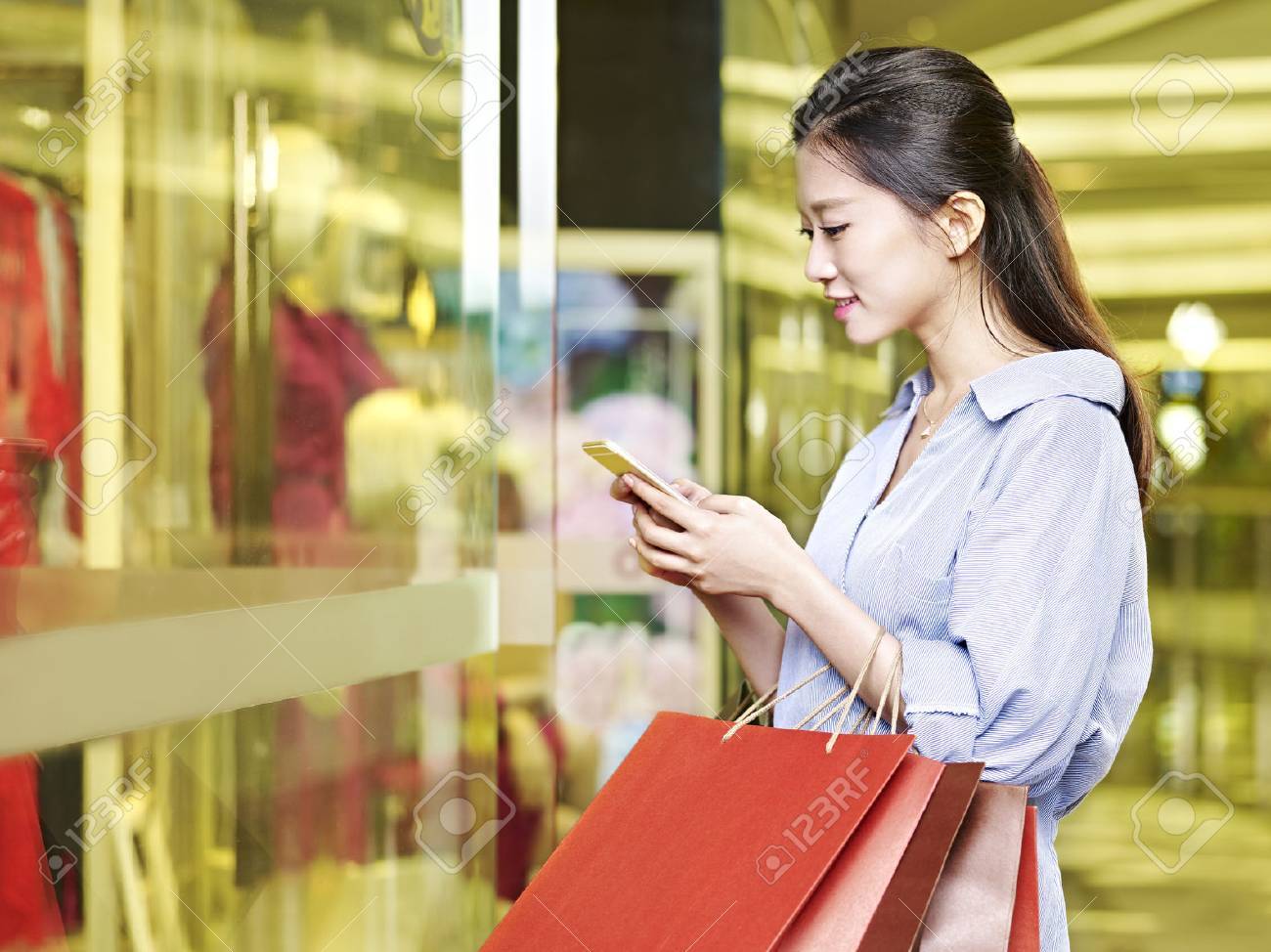 探している若いアジア女性のショッピング モールやデパートで買い物しながら携帯電話を使用して の写真素材 画像素材 Image 探している若いアジア女性のショッピング モールやデパートで買い物しながら携帯電話を使用して の写真素材 画像素材 Image