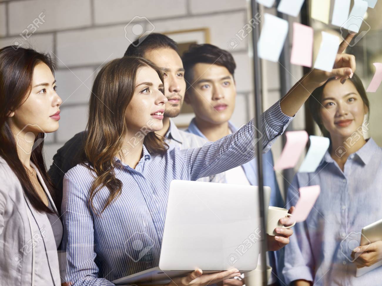 team of young asian and caucasian entrepreneurs discussing business using laptop, digital tablet and adhesive notes in office. - 91431270 team of young asian and caucasian entrepreneurs discussing business using laptop, digital tablet and adhesive notes in office. - 91431270