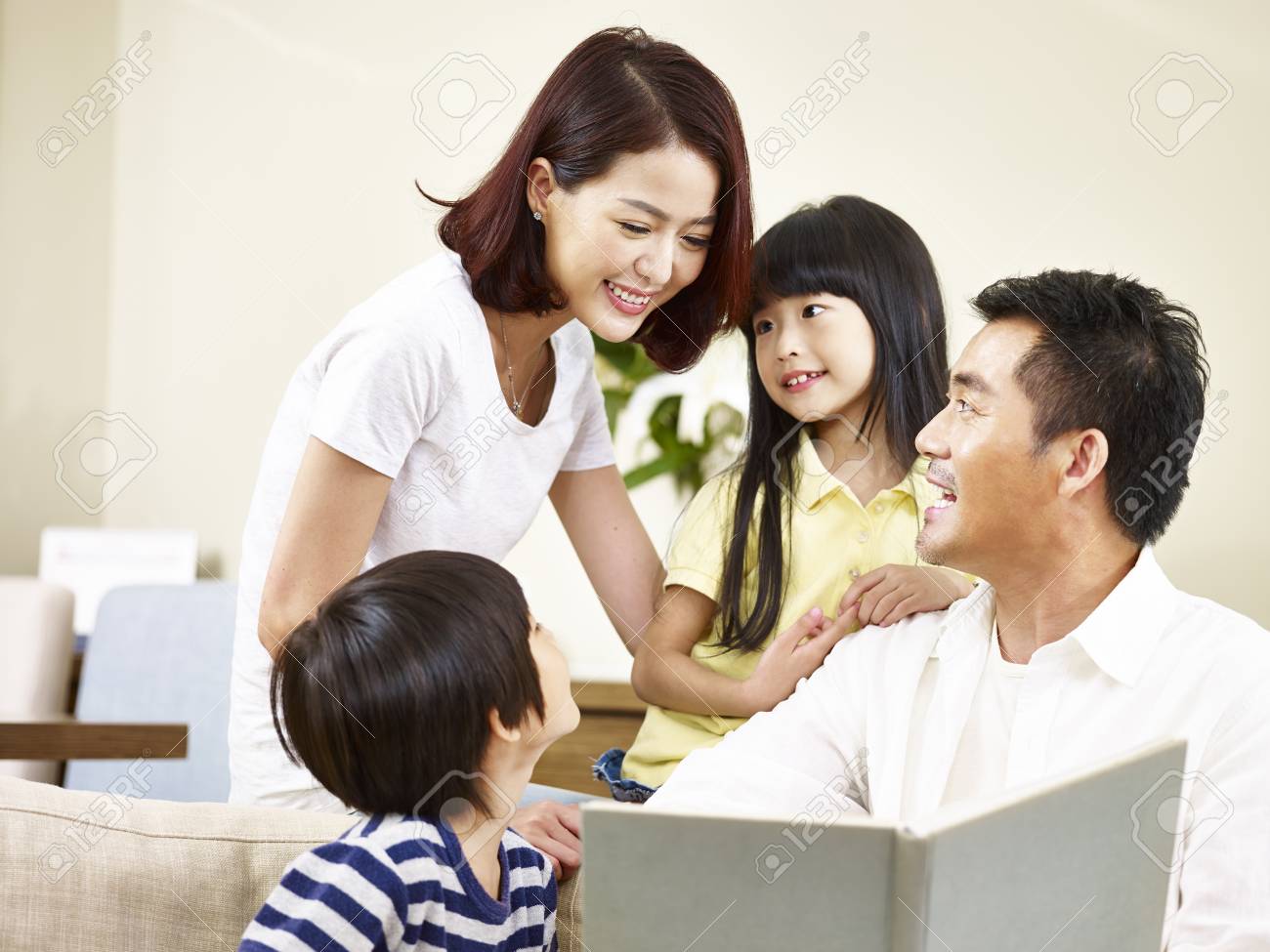 asian parents mother and father and two children son and daughter reading a book telling a story together. - 91878561 asian parents mother and father and two children son and daughter reading a book telling a story together. - 91878561