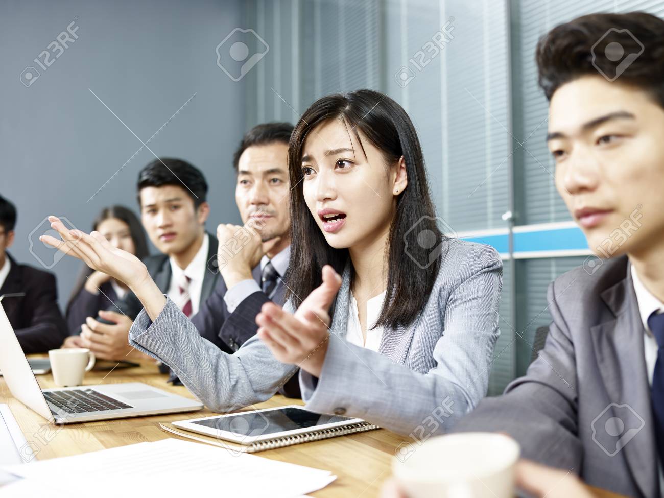 young asian business woman executive engaging in a heated discussion during meeting. - 106415000 young asian business woman executive engaging in a heated discussion during meeting. - 106415000