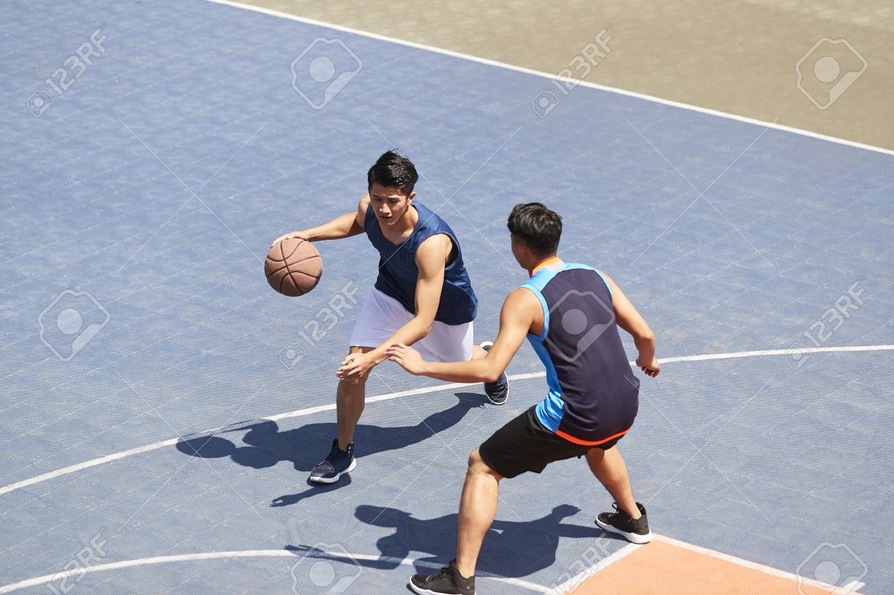 two young asian basketball players playing one on one on outdoor court. - 113197321 two young asian basketball players playing one on one on outdoor court. - 113197321
