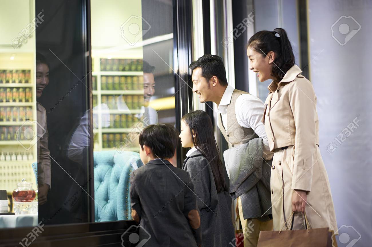happy asian family with two children looking into a shop window in shopping mall - 115866247 happy asian family with two children looking into a shop window in shopping mall - 115866247