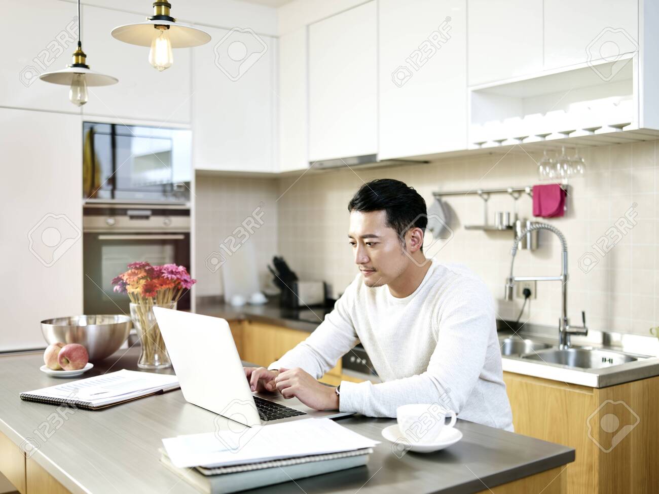 young asian man working from home sitting at kitchen counter using laptop computer - 132759870 young asian man working from home sitting at kitchen counter using laptop computer - 132759870