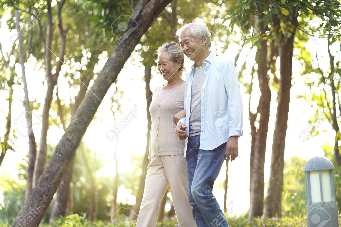 happy senior asian couple walking talking relaxing outdoors in park - 134270367 happy senior asian couple walking talking relaxing outdoors in park - 134270367