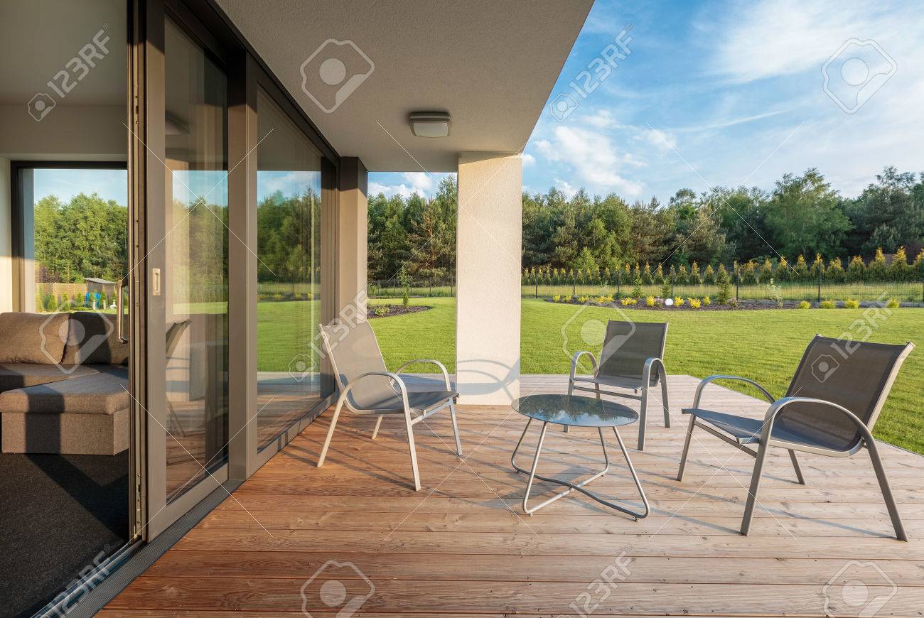 Stilvolle Terrasse Mit Holzboden Und Blick Auf Den Garten Einfache Gartenmobel Set Lizenzfreie Fotos Bilder Und Stock Fotografie Image 58747007