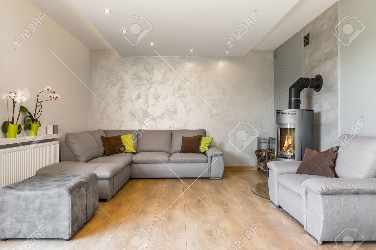 Spacieux salon avec un très grand canapé, une cheminée de style industriel, des panneaux de plancher en bois et une finition murale décorative
