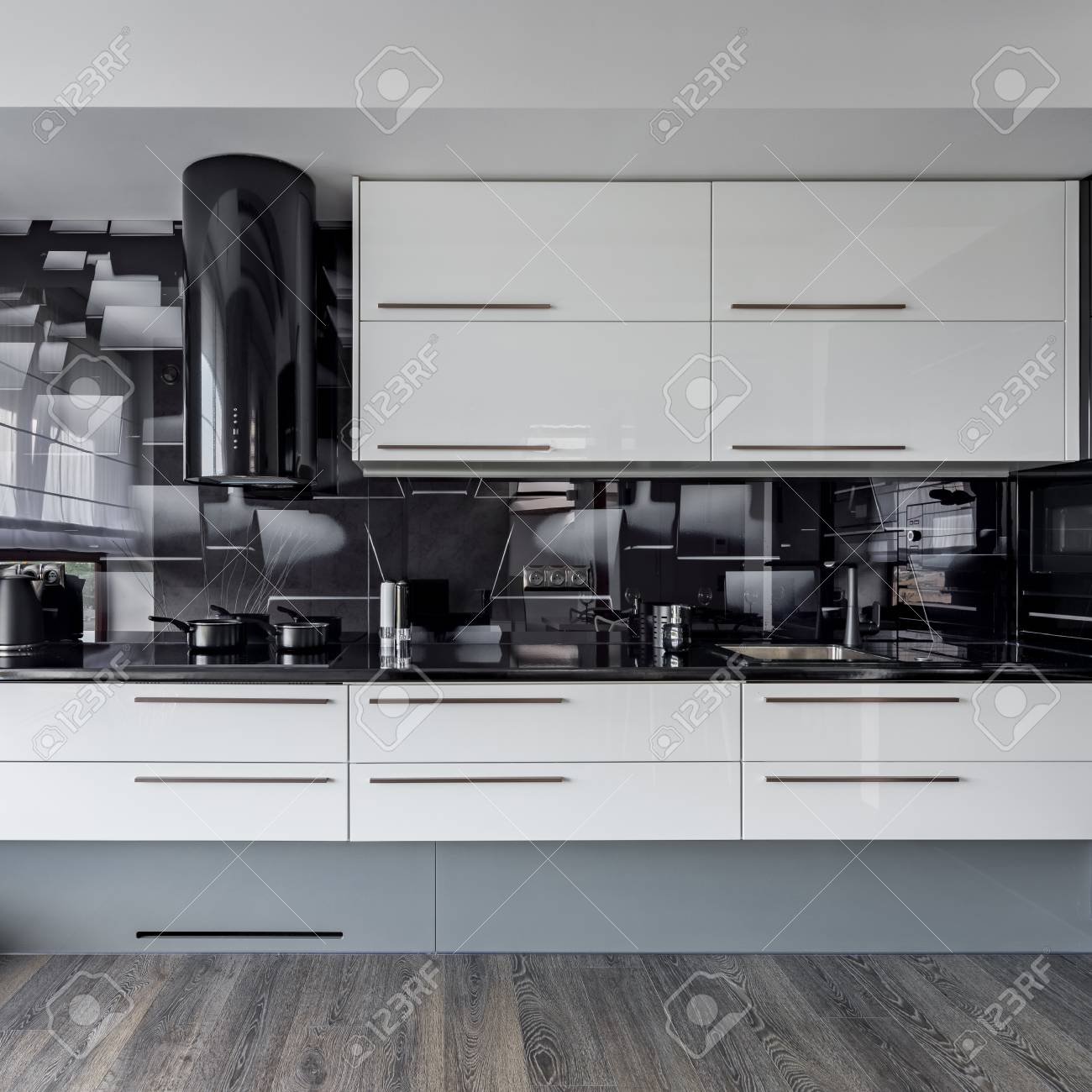 Modern Kitchen With White Cupboards And Black Wall Tiles Stock Photo