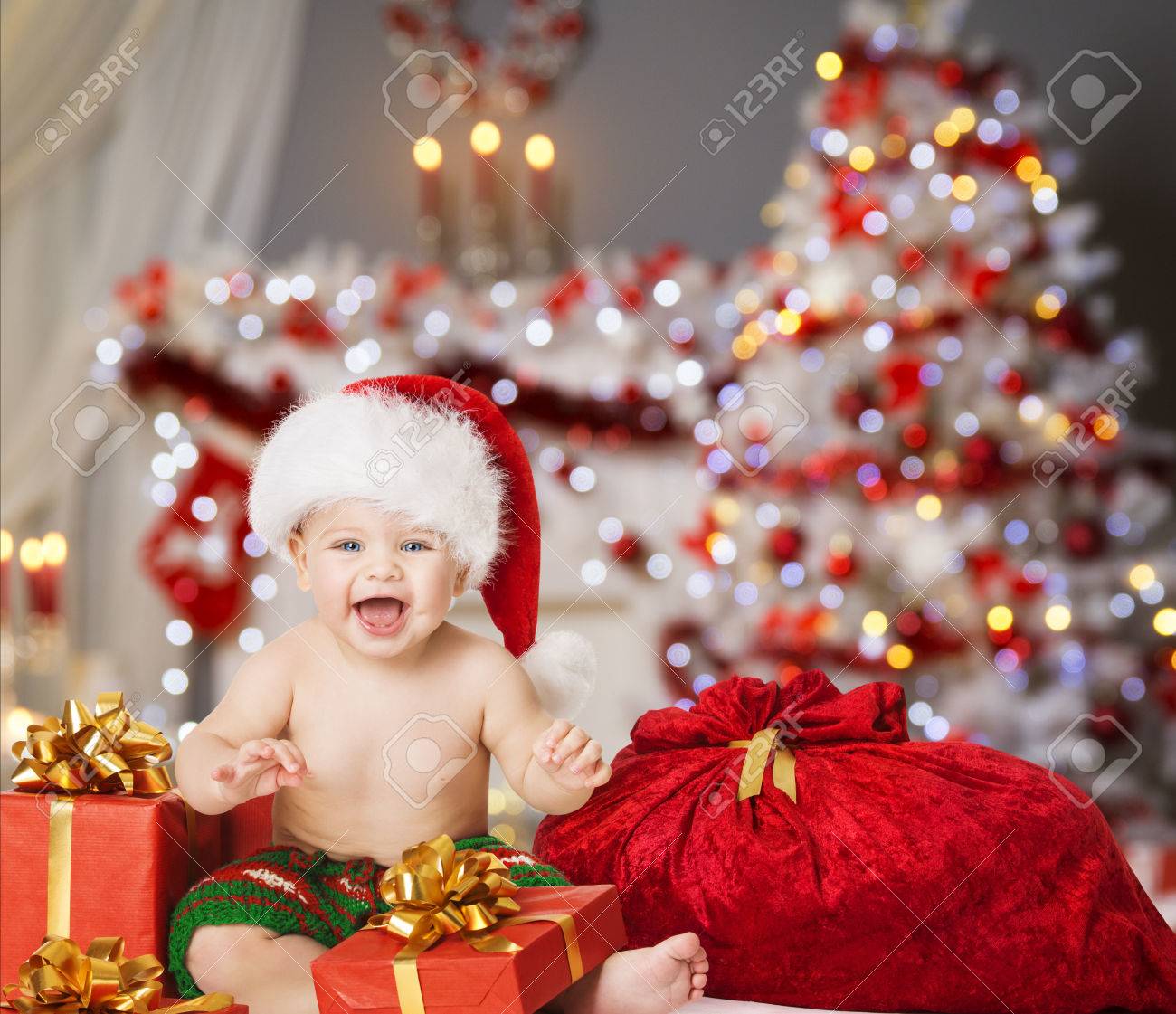 Christmas Baby in Santa Hat, Kid Boy with Xmas Present Gift Box and Bag - 65114199 Christmas Baby in Santa Hat, Kid Boy with Xmas Present Gift Box and Bag - 65114199