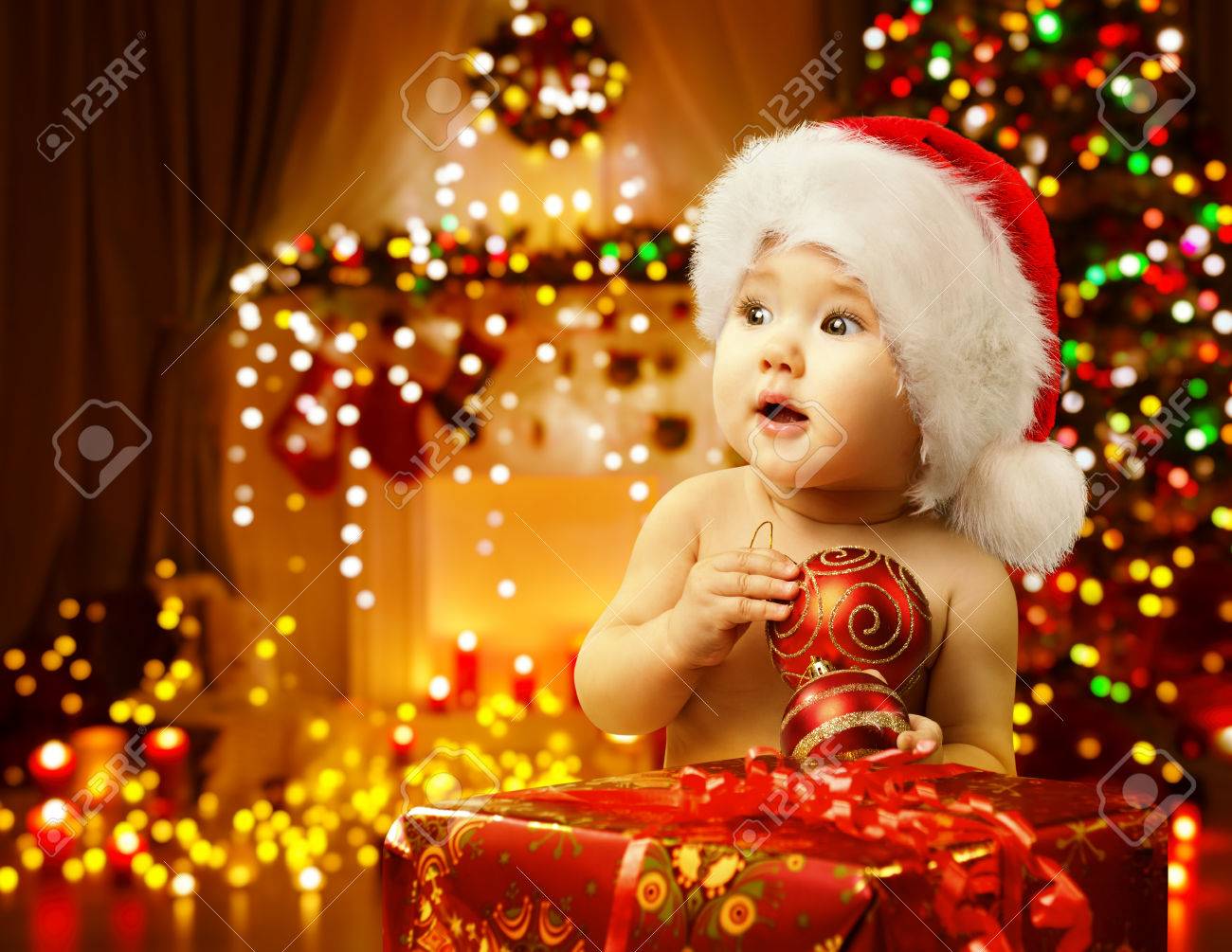 Christmas Baby Opening Present, Happy Kid in Santa Hat, Xmas Gift Box, Child Looking Side - 63802539 Christmas Baby Opening Present, Happy Kid in Santa Hat, Xmas Gift Box, Child Looking Side - 63802539