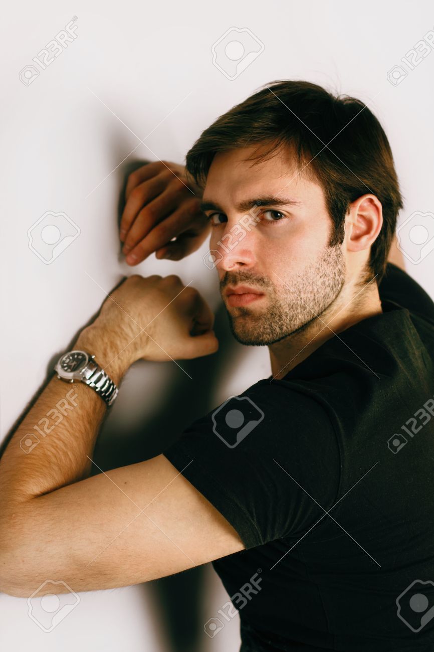 茶色の髪と黒い T シャツと彼の左手の銀の腕時計の明るい目とハンサムな Smartlooking 男はフレームに見つめてと怒っている探している悪のファッションの肖像画はグランブルーから帰って の写真素材 画像素材 Image