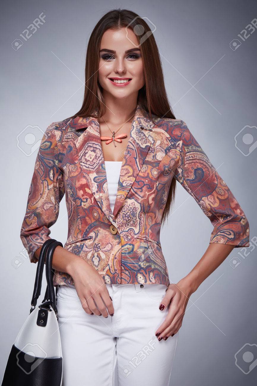 美容流行の女性シルク ブラウス ジャケットとパンツ ファッション スタイル見てビジネス服会議と長いブルネットの髪 日焼け肌メイク パーティーでセクシーな女性のカジュアルな手にバッグ レディーを保持します の写真素材 画像素材 Image