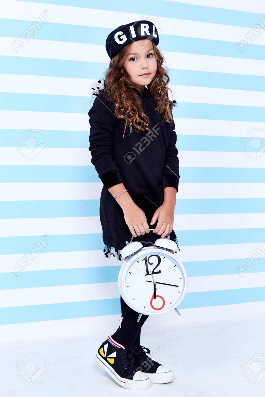 女子高生の生徒制服のベレー帽ソックスのための学校の小さな女の子のドレスは ファッションスタイルの服子供の子供の子供の子供の子供のかわいい顔を保持するファッションスタイルの服を学ぶ楽しい笑顔のカーリーヘアおもちゃの研究のための大きな時計の遊びを保持します