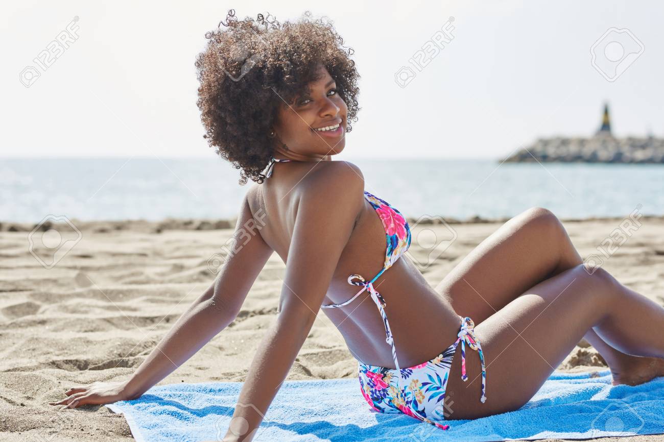 young happy afro american woman sitting on beach stock photo