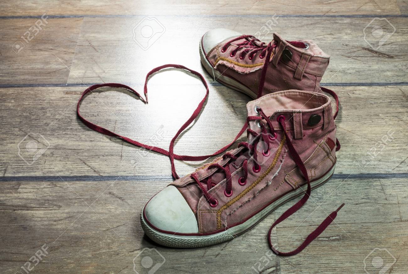 Usado, Zapatillas De Deporte Sucias, Con Cordones De Los Zapatos En Forma De Corazón Sobre Un Suelo De Madera. Fotos, Retratos, Imágenes Y Fotografía De Libres De Derecho. Image 51372108.