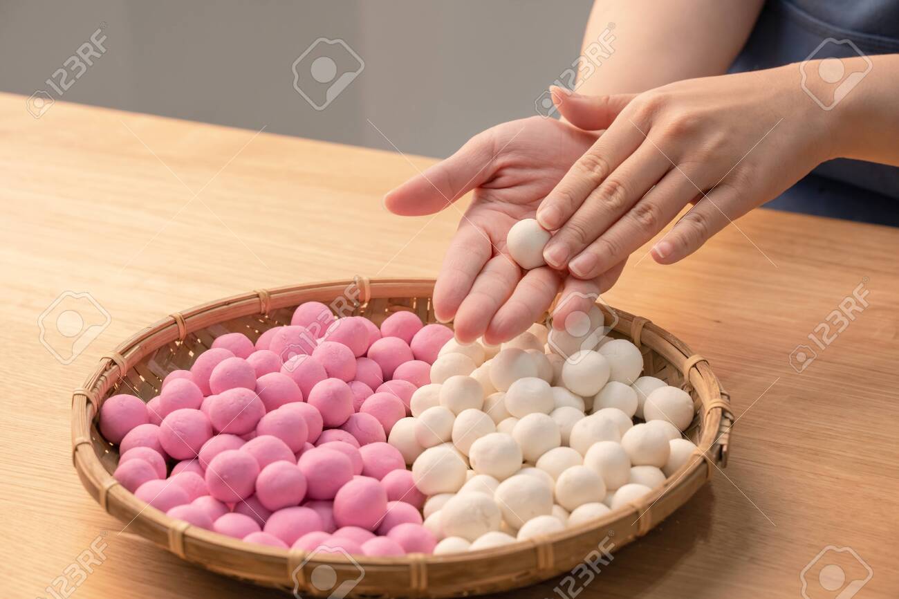 An Asia woman is making Tang yuan, yuan xiao, Chinese traditional food rice dumplings in red and white for lunar new year, winter festival, close up. - 135452743 An Asia woman is making Tang yuan, yuan xiao, Chinese traditional food rice dumplings in red and white for lunar new year, winter festival, close up. - 135452743