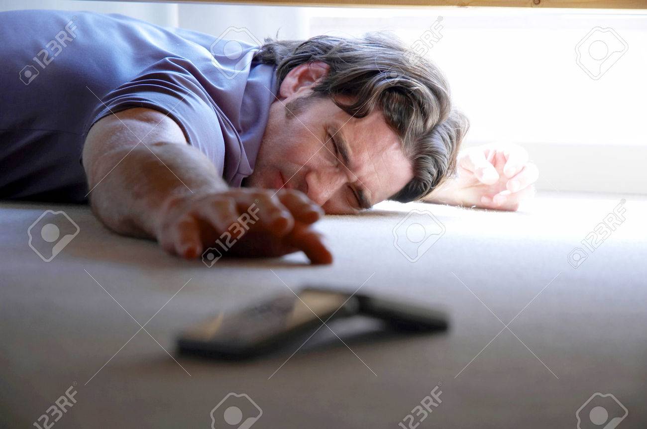 ベッドの下から手の電話を取得しようとすると 男 の写真素材 画像素材 Image