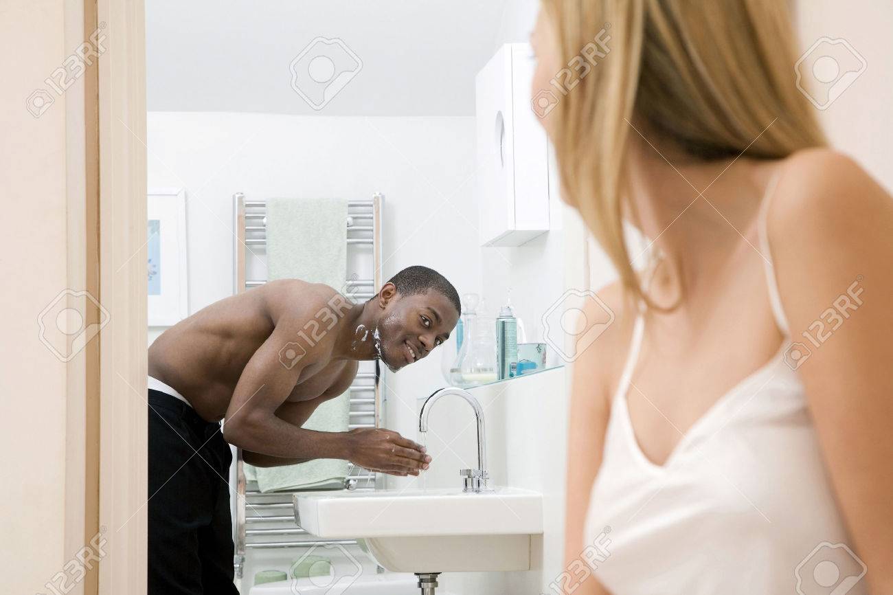 Woman Watching Man Washing His Face In The Bathroom Stock Photo