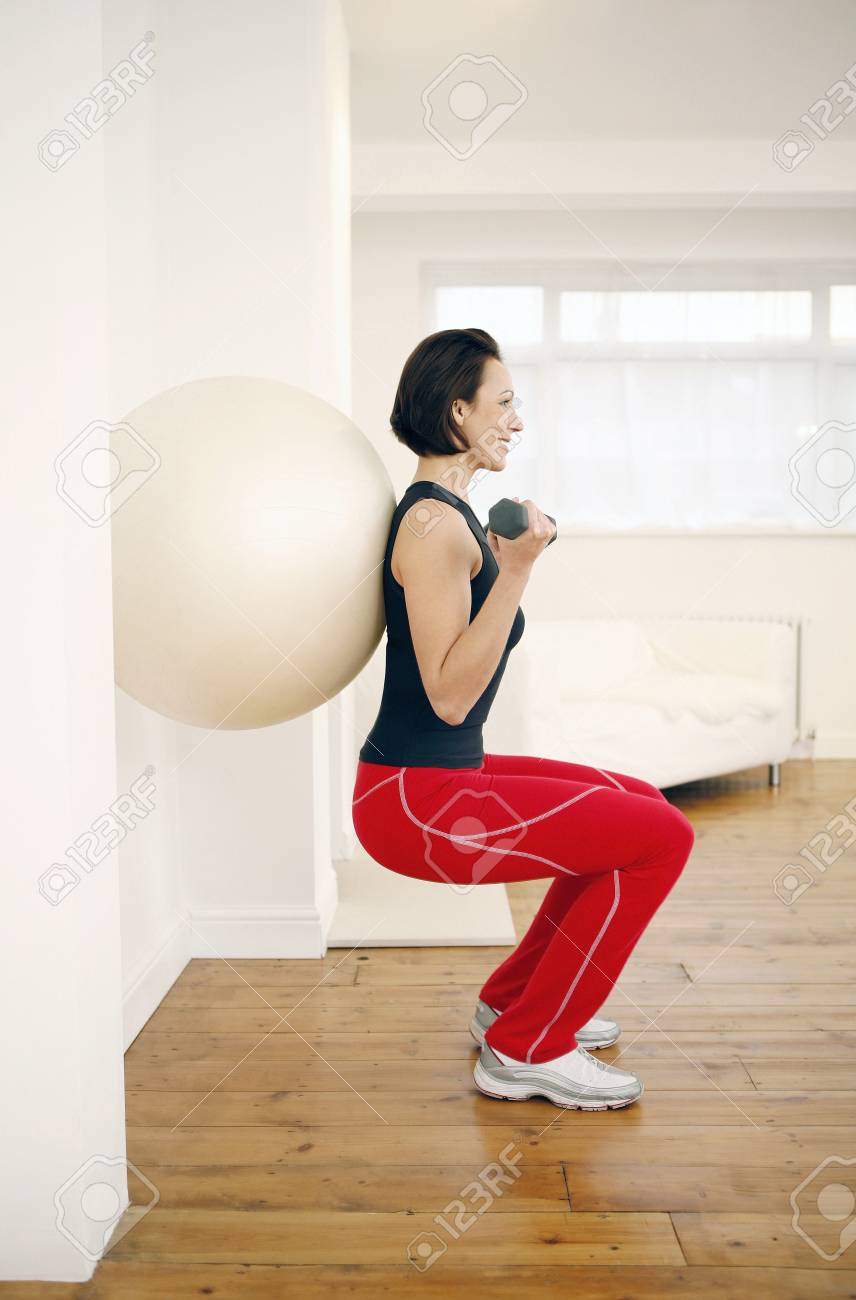 Mujer Presionando Bola De La Aptitud Contra La Pared Mientras