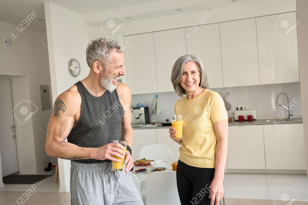 Healthy sporty happy seniors family couple drinking juice and laughing at home. - 168869512 Healthy sporty happy seniors family couple drinking juice and laughing at home. - 168869512