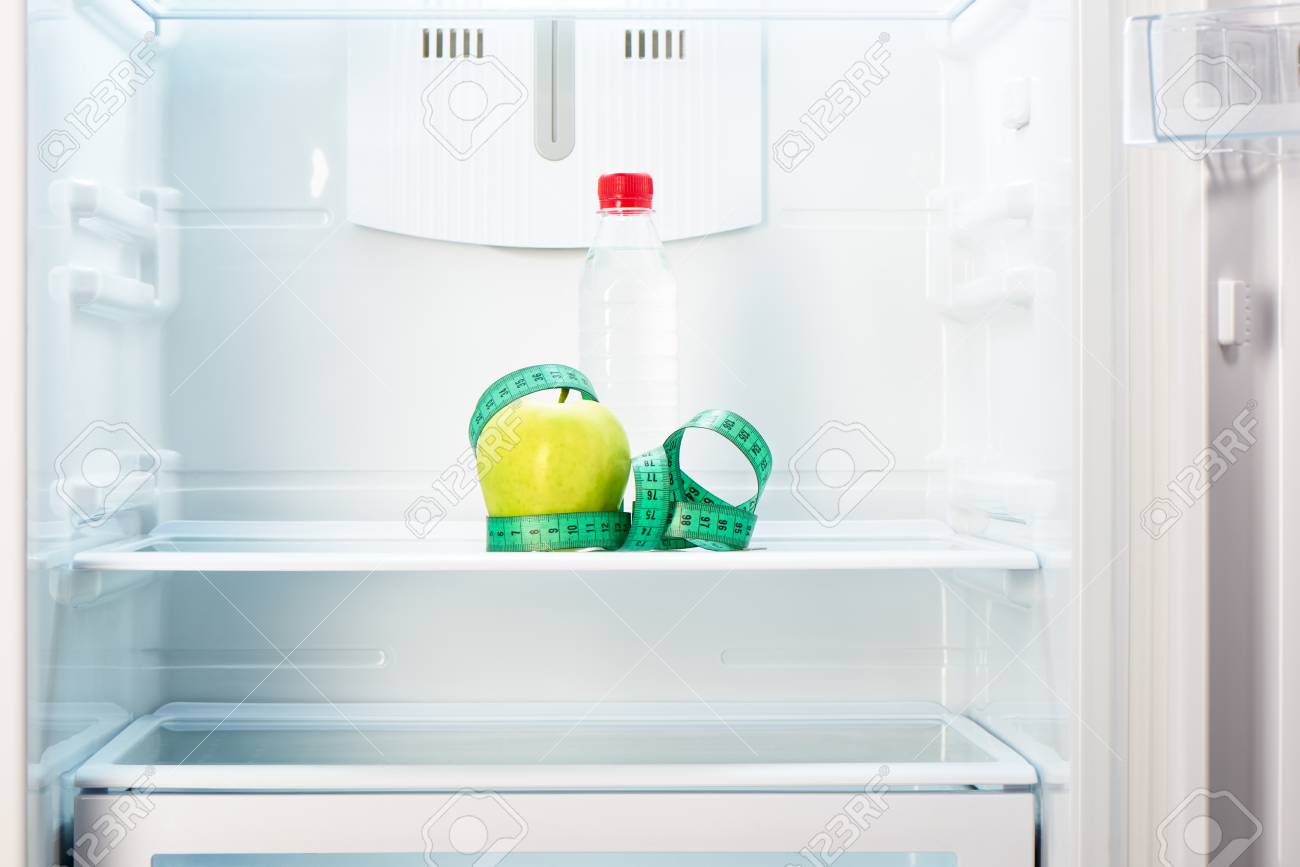 Kühlschrank Regal : Flasche wasser mit maßband auf dem regal der offenen leeren Kühlschrank Regal : Flasche wasser mit maßband auf dem regal der offenen leeren
