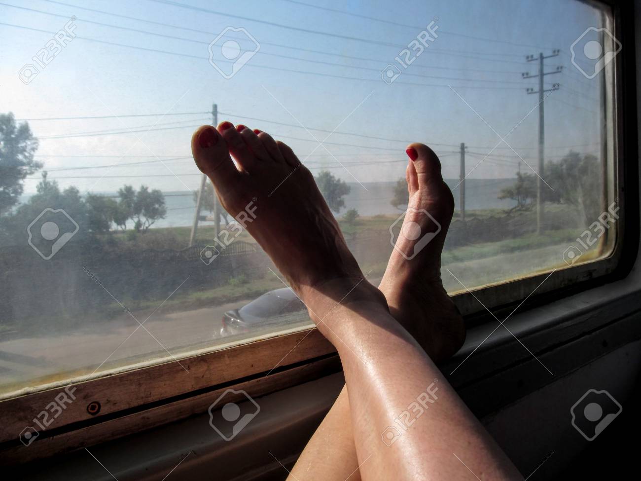 Stock Photo The Concept Of Travel With Convenience Female Feet In The Train Window Window Of Public Transport Womens Legs With A Red Pedicure Stock Photo The Concept Of Travel With Convenience Female Feet In The Train Window Window Of Public Transport Womens Legs With A Red Pedicure