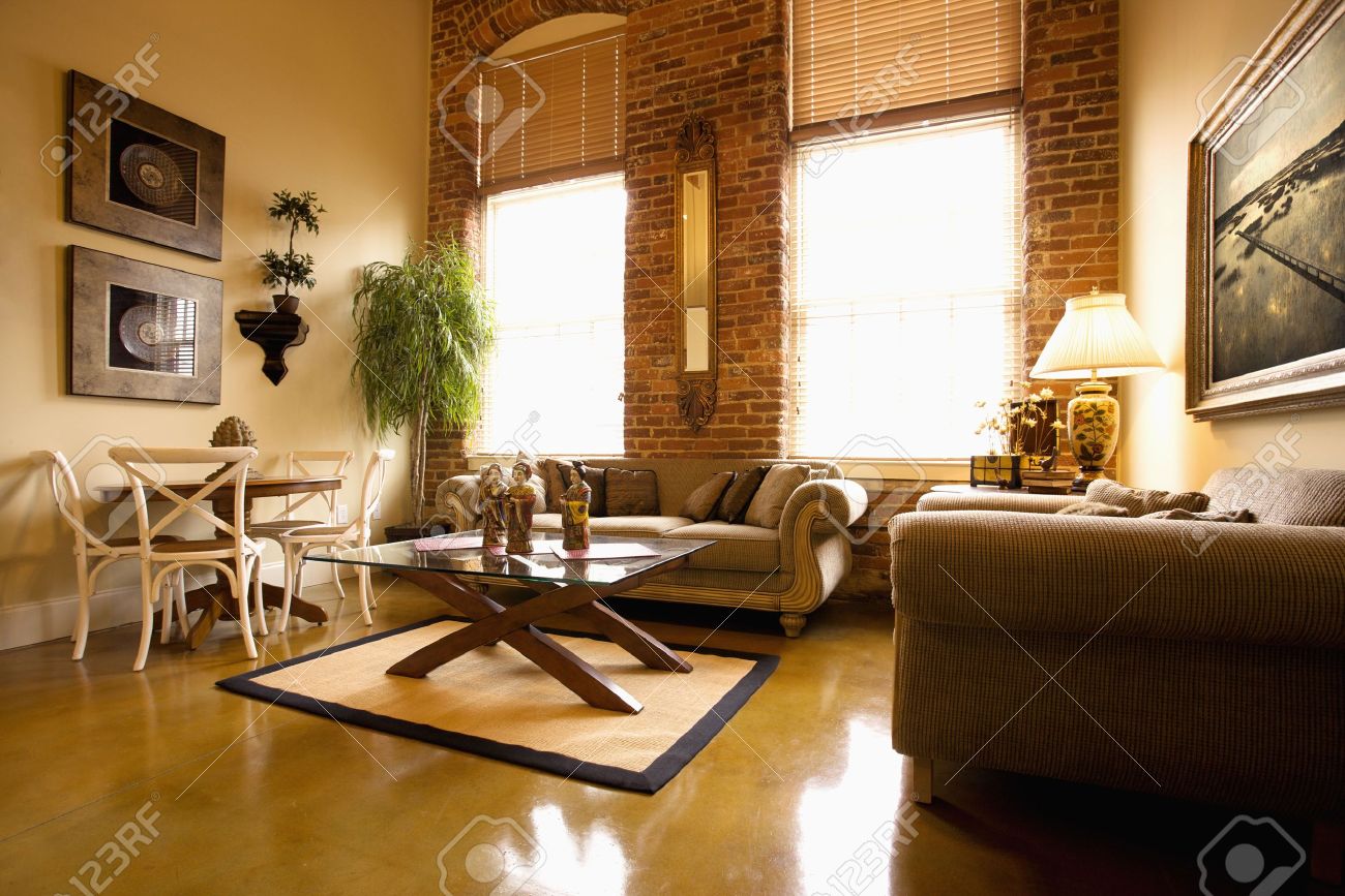 interior of furnished living room with large windows and brick interior of furnished living room with large windows and brick
